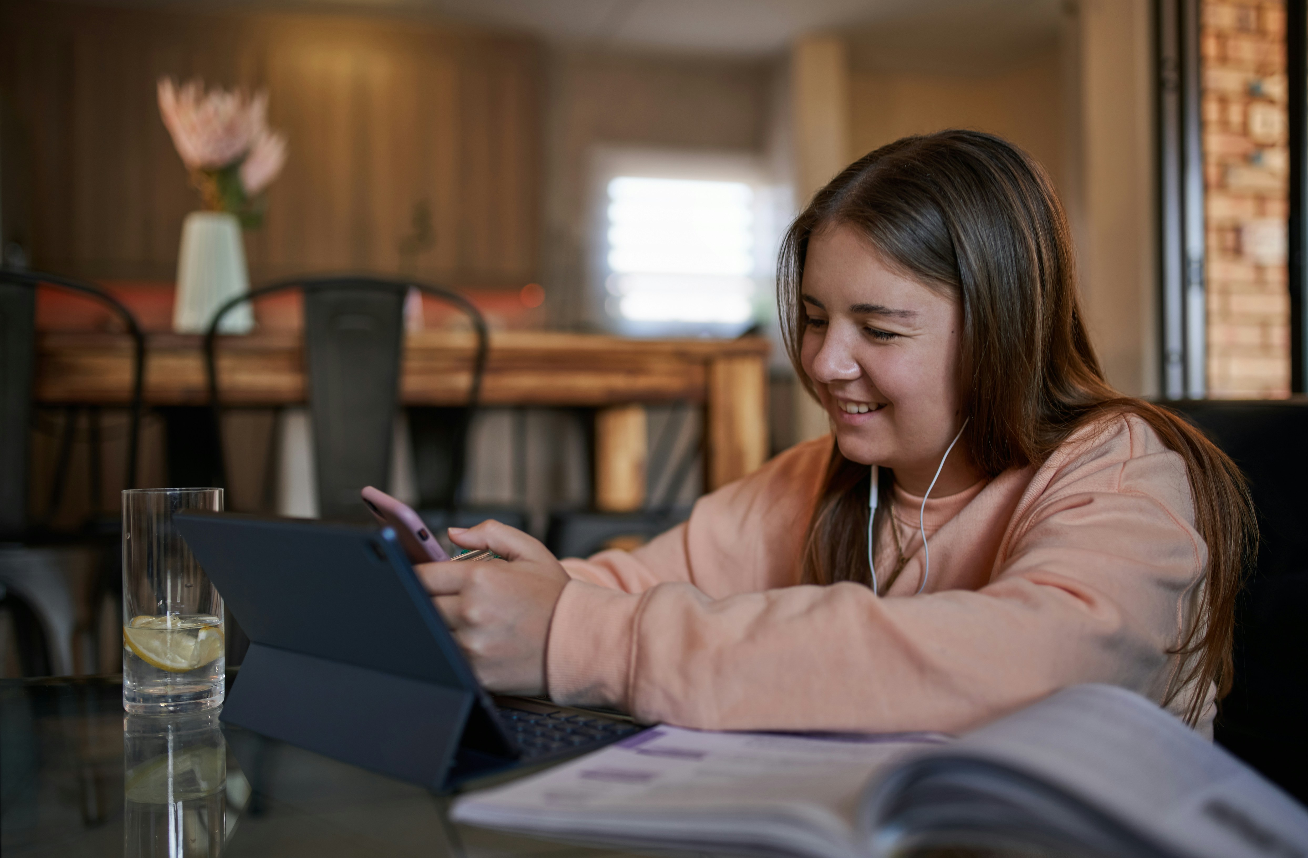 Teen girl studying at home with a tablet and earbuds